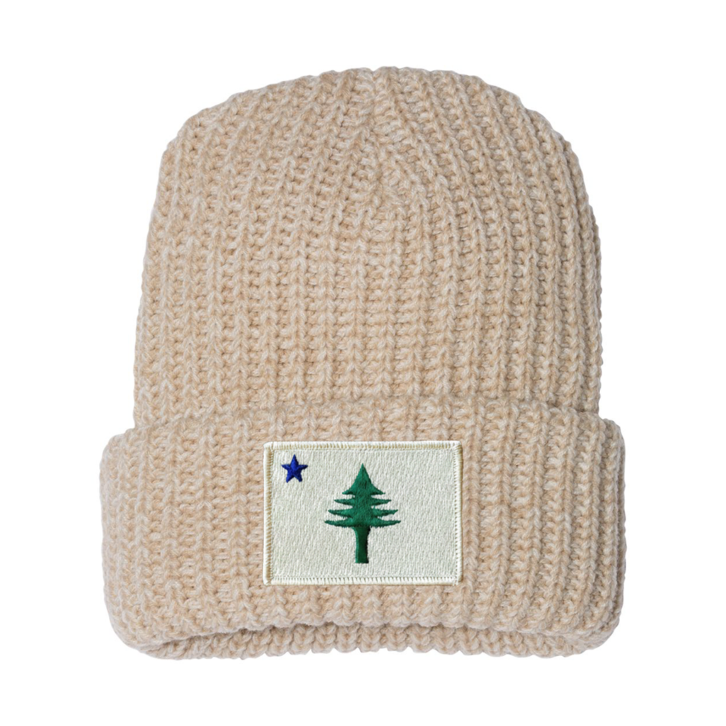 Beige knit beanie with a patch featuring a tree and star from the 1901 Maine state flag on a white background