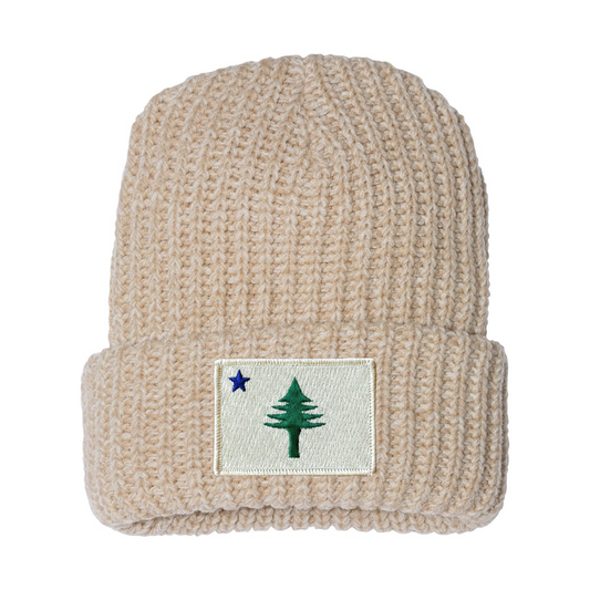 Beige knit beanie with a patch featuring a tree and star from the 1901 Maine state flag on a white background
