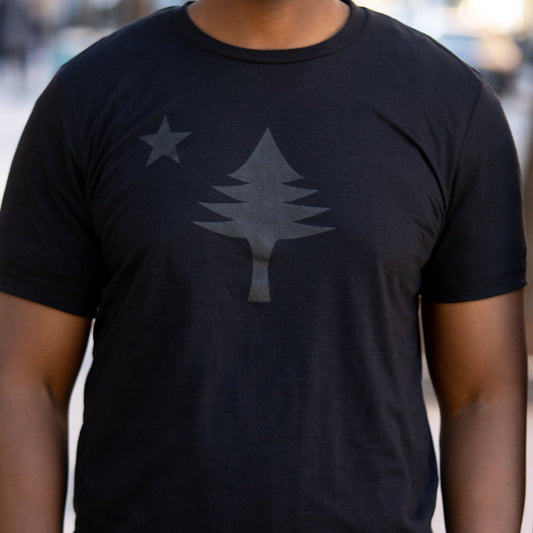 Black t-shirt with a star and tree design worn by a person.